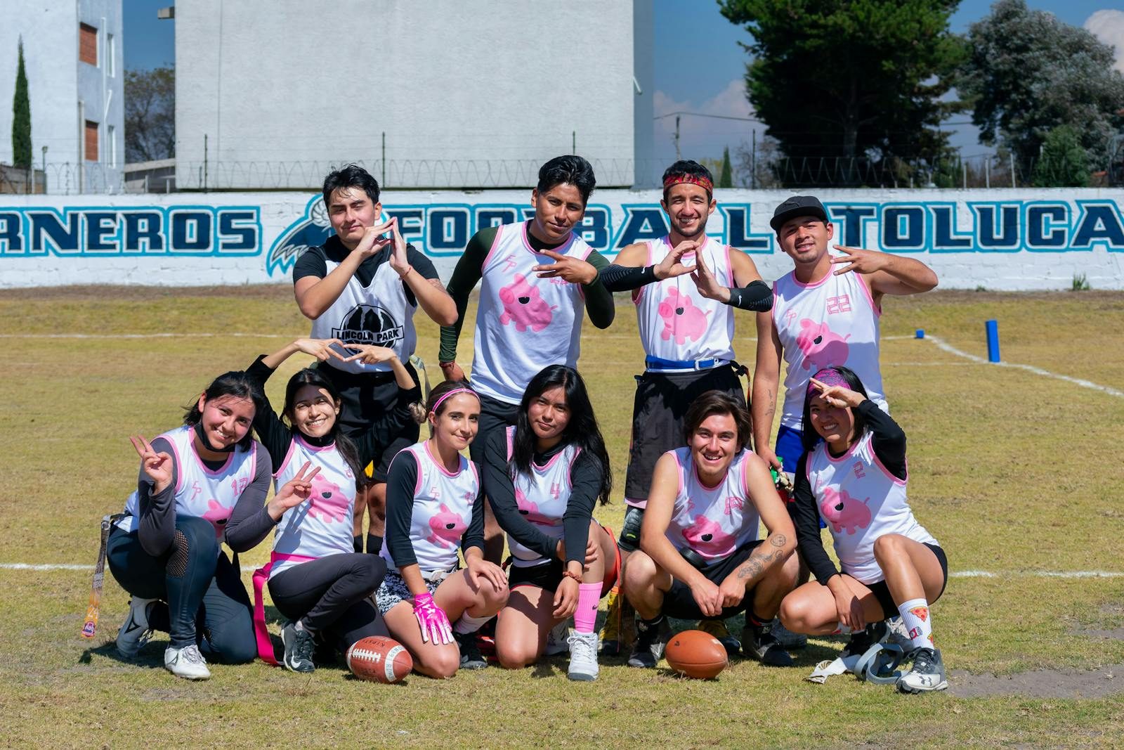 A youth football team poses on a sunny day in Toluca, Mexico, showcasing teamwork and sportsmanship.