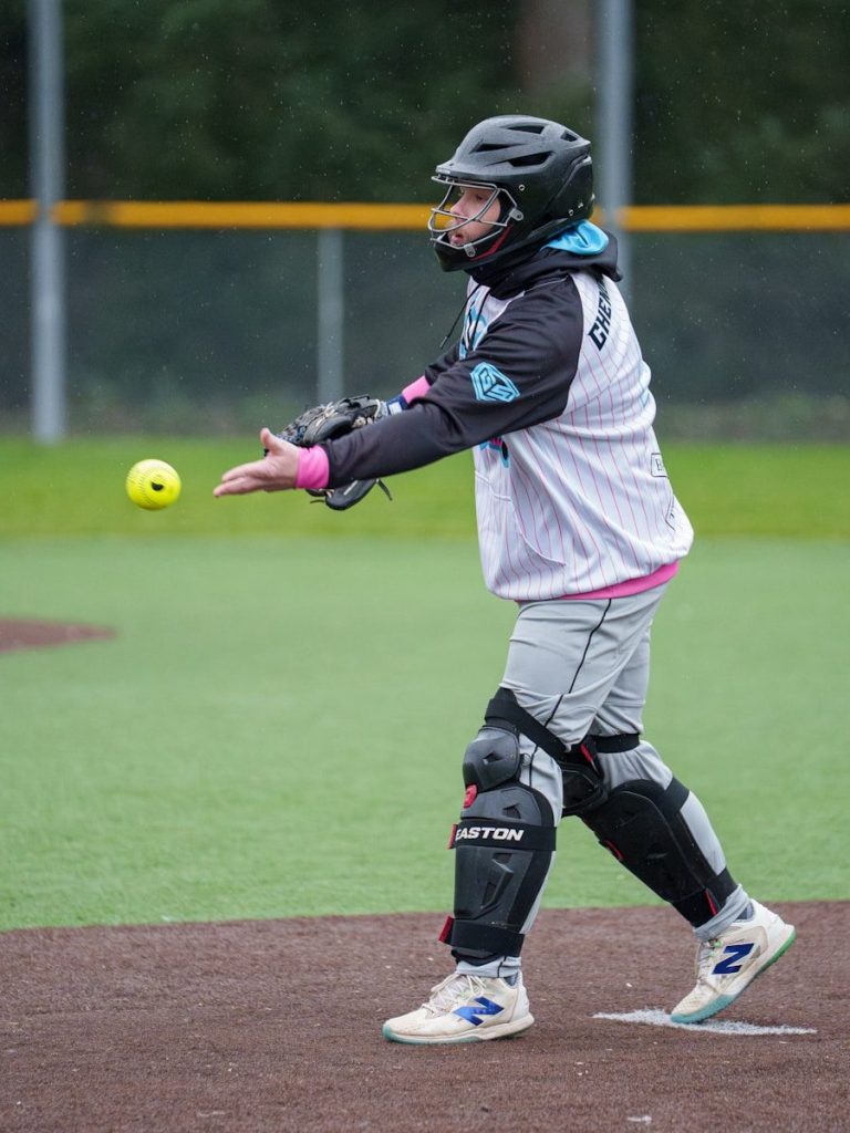 Catcher in protective gear prepares to catch softball