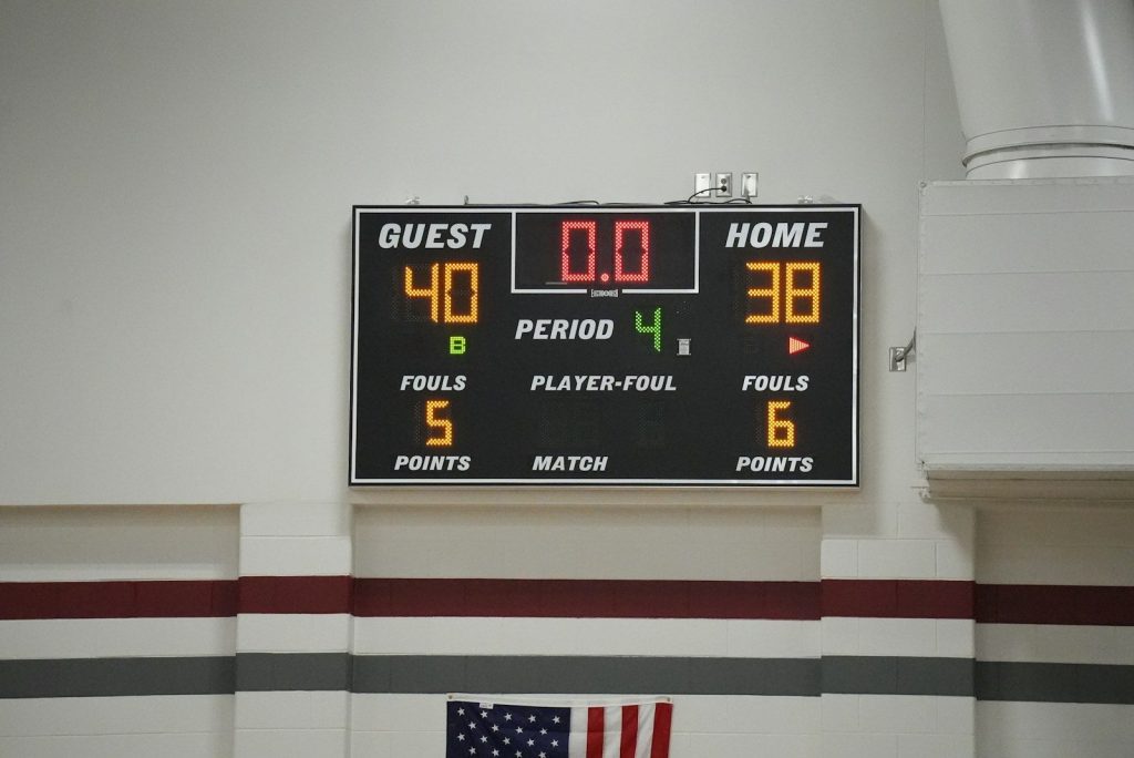 a scoreboard in a gym with a flag on the floor